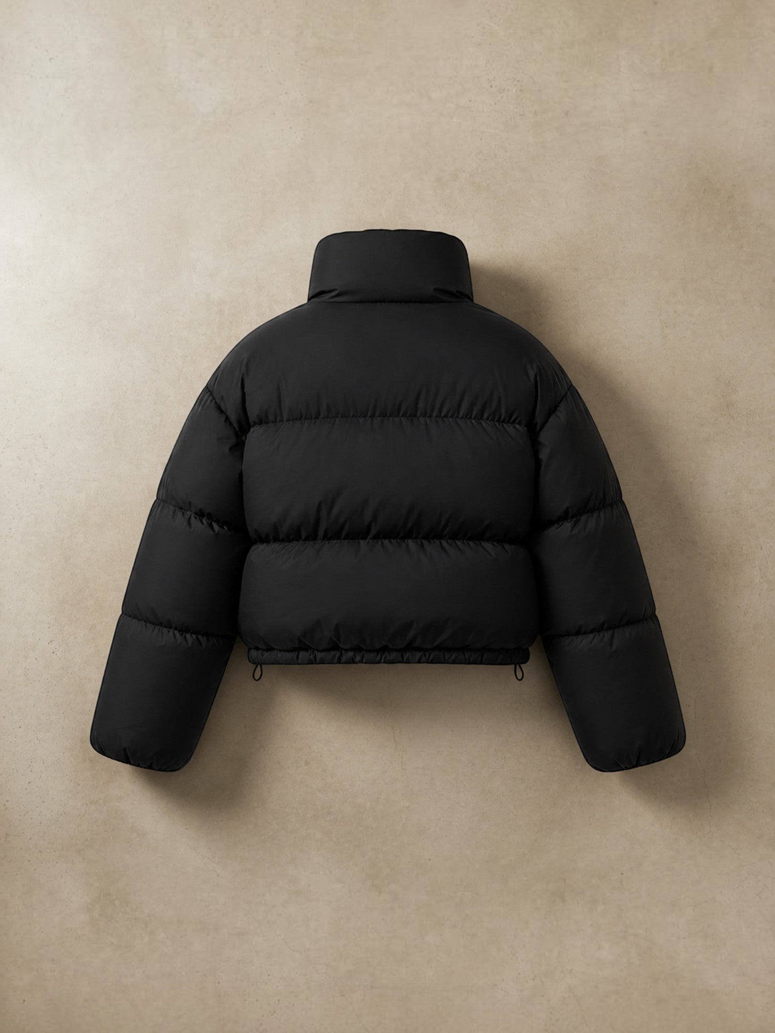 Chaqueta puffer cropped negra cozyvibe con cuello alto y diseño acolchado, vista trasera sobre fondo neutro.