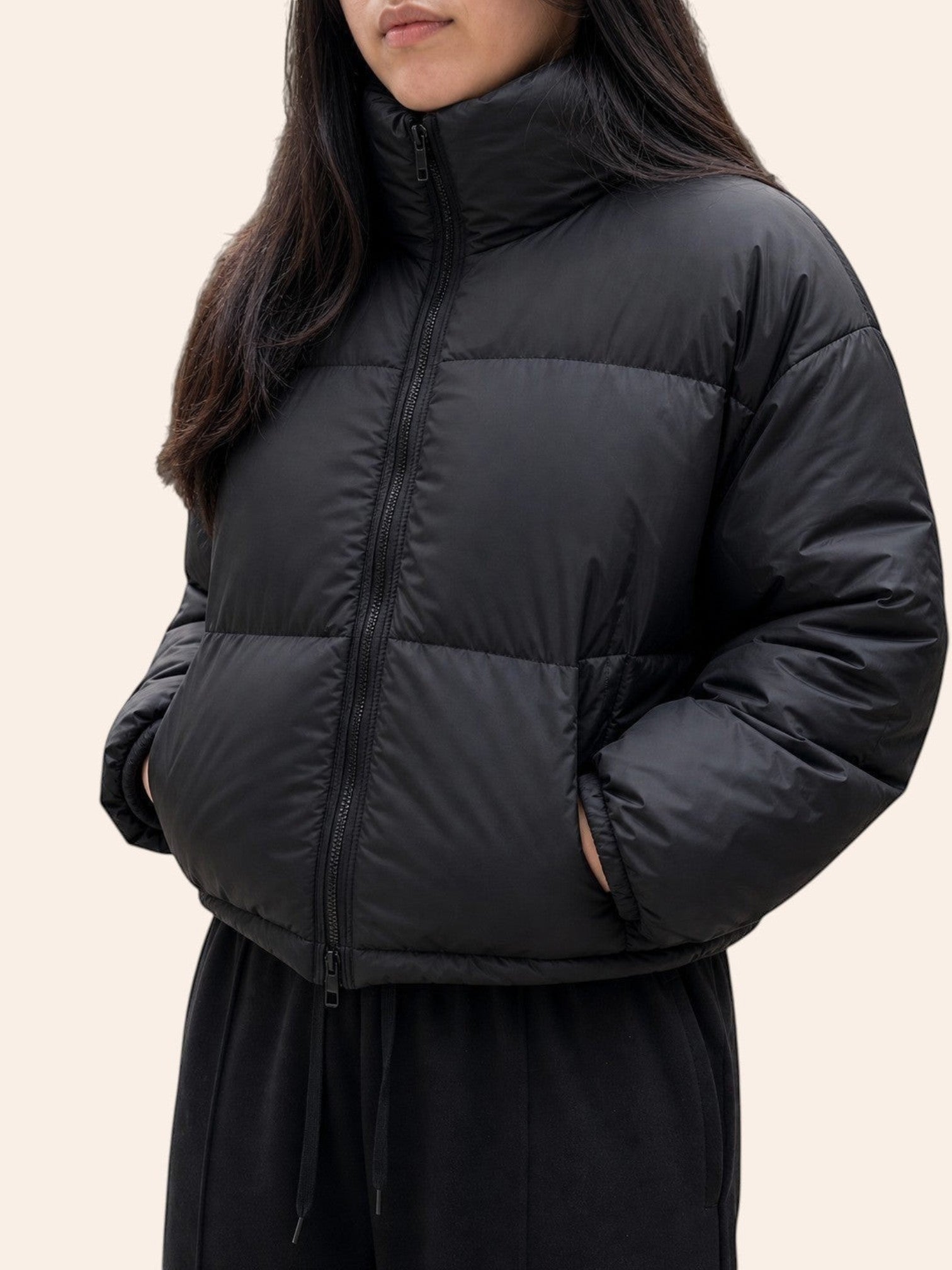 Modelo vistiendo chaqueta puffer negra cropped de cozyvibe con cuello alto y cierre frontal en entorno urbano