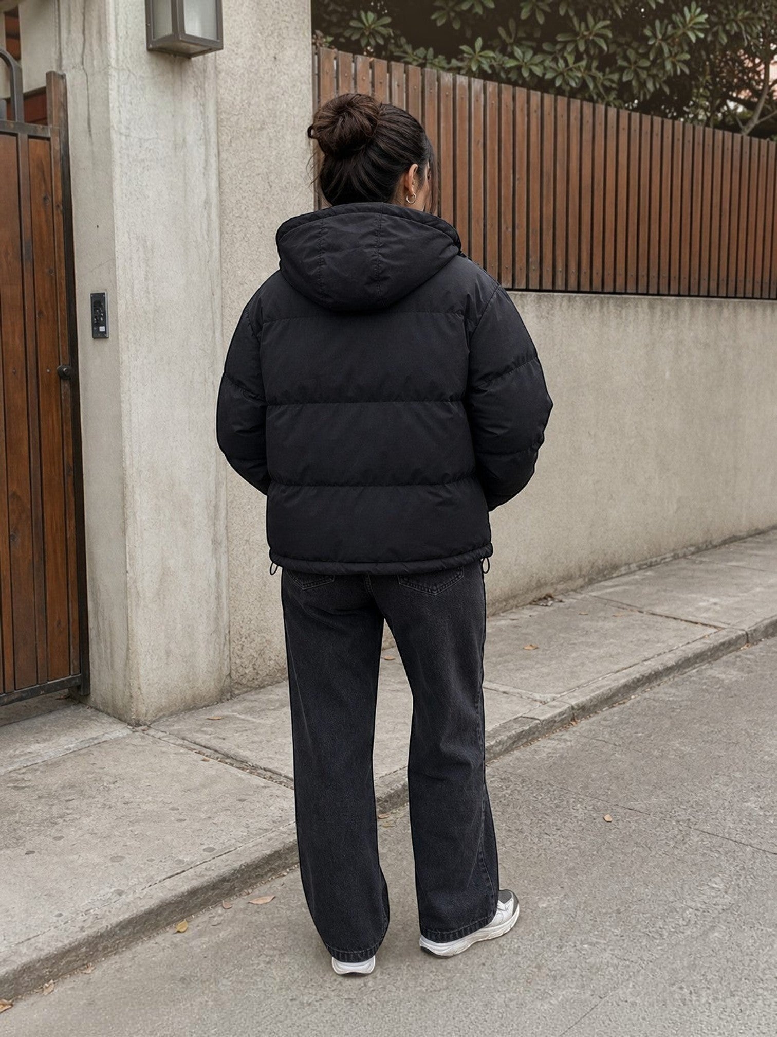 Chaqueta puffer negra oversize unisex de cozyvibe con capucha, vista trasera de una persona en entorno urbano