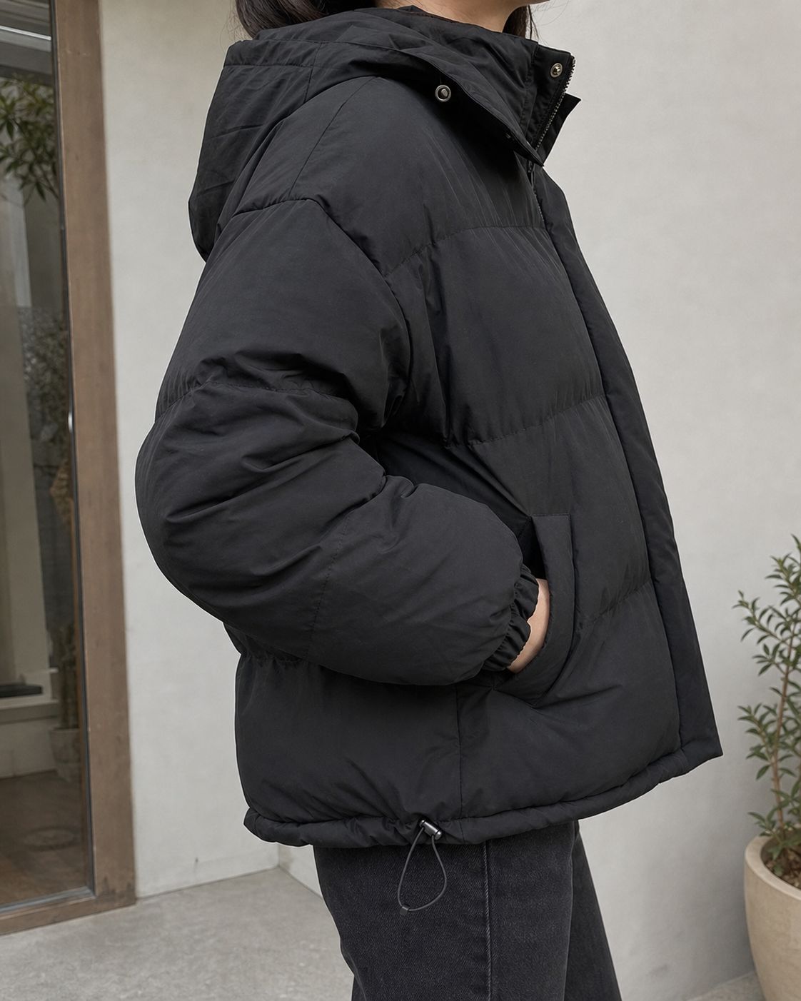Detalle de capucha y bolsillo de la chaqueta puffer negra